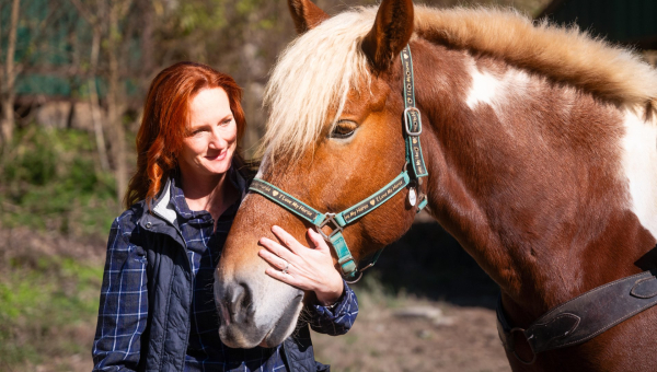 Woman stands with horse as in Georgetown, Kentucky, getting ready to horseback ride through the Kentucky backwoods.